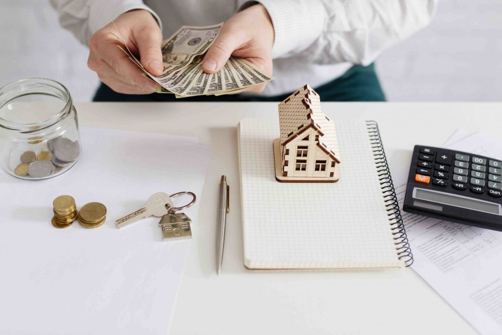 Persona contando dinero con una calculadora y libreta sobre la mesa.