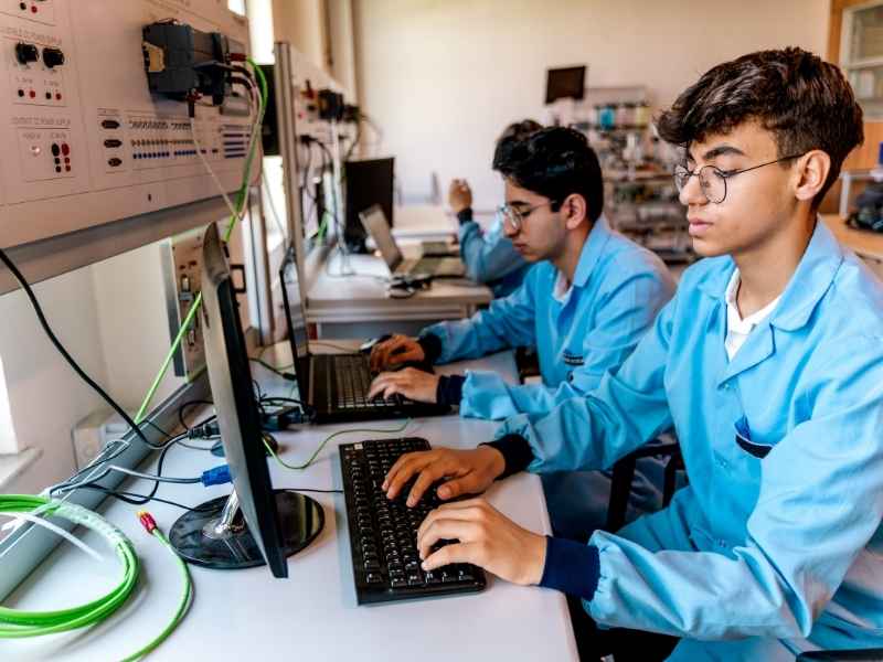Estudiantes en laboratorio tecnológico aprendiendo habilidades técnicas orientadas a la empleabilidad.