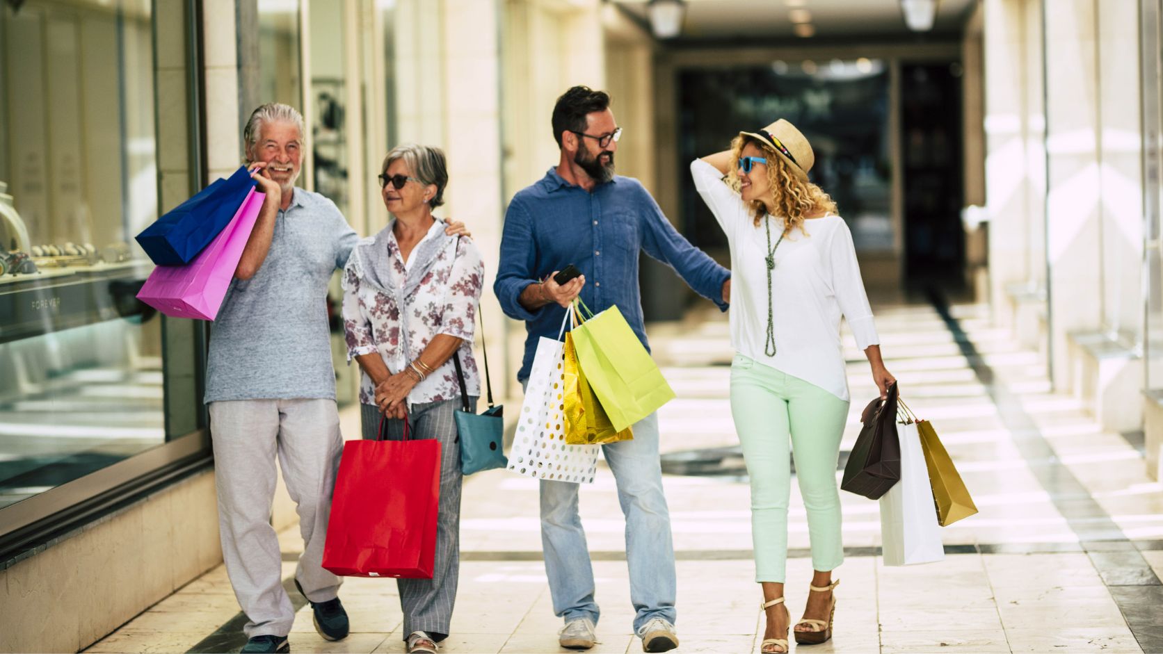 Grupo de personas caminando con bolsas de compras por una zona comercial, reflejando la experiencia de compra y convivencia.